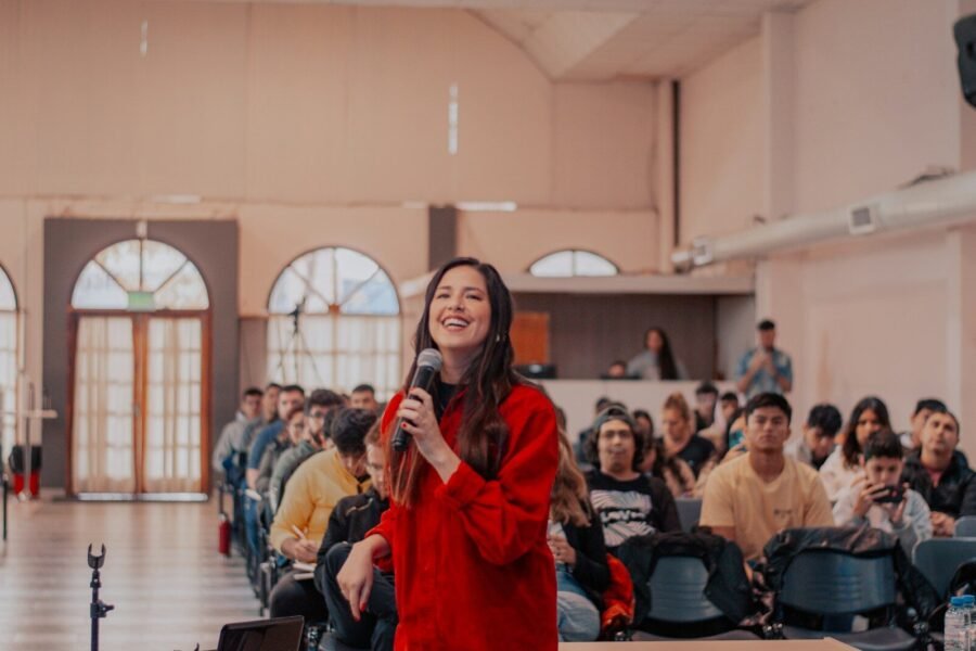 a woman standing in front of a crowd holding a microphone