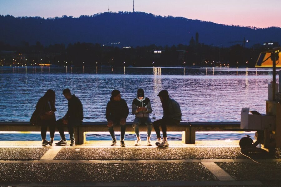 five people sitting near body of water